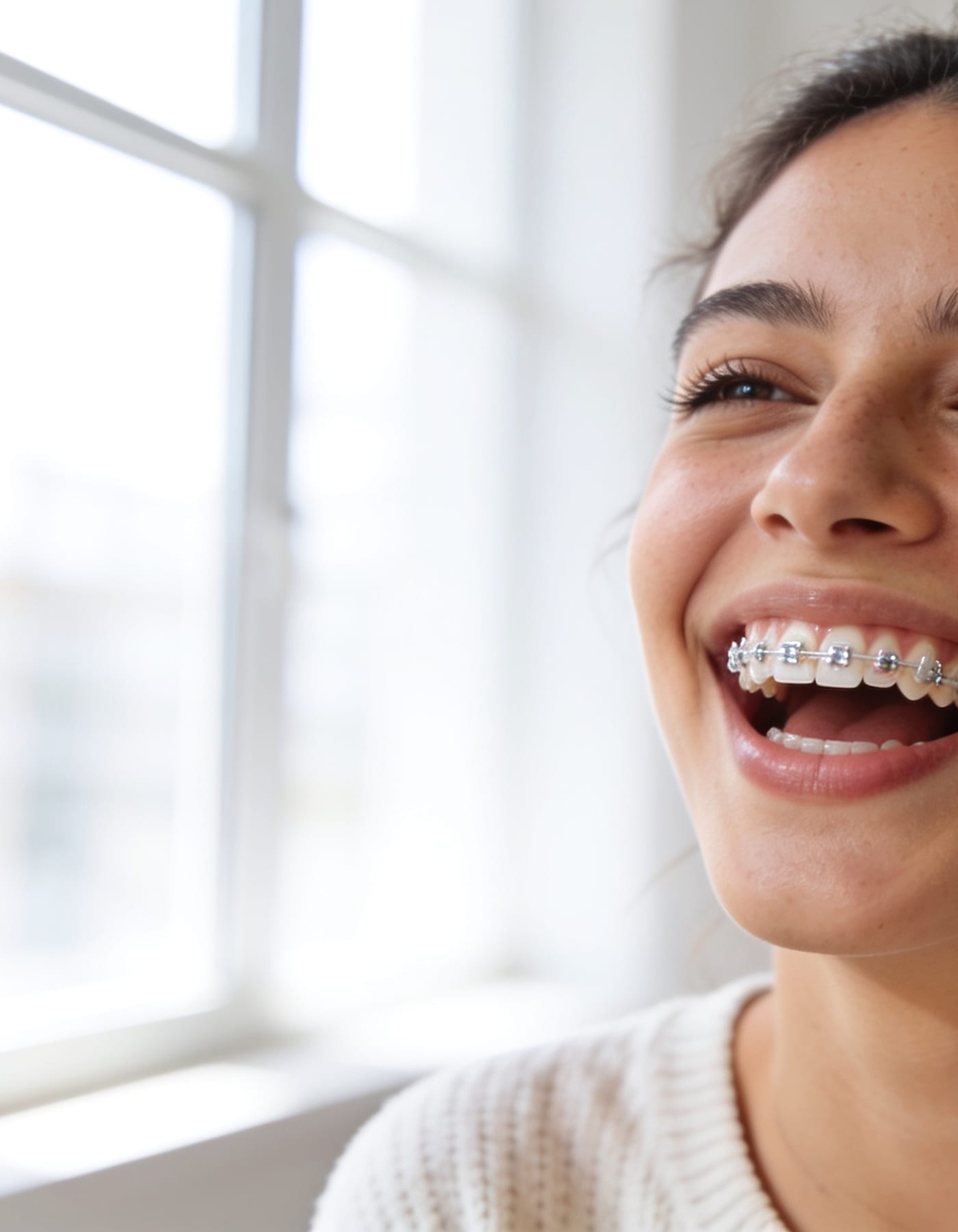 Paciente joven sonriendo con brackets metálicos durante su tratamiento de ortodoncia